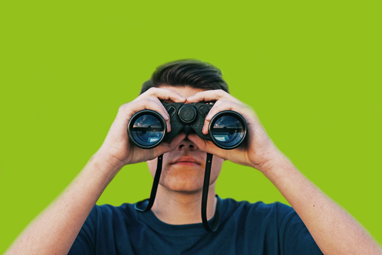 Jobangebote - Druckerei Hamburg Jobs Person frontal hält Fernglas vors Gesicht, grüner Hintergrund - Druckerei Hamburg Jobs